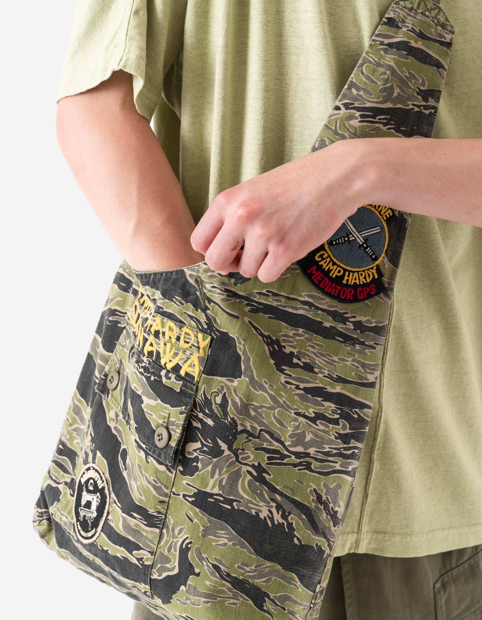 Person wearing a green t-shirt and camouflage shorts with visible branding.