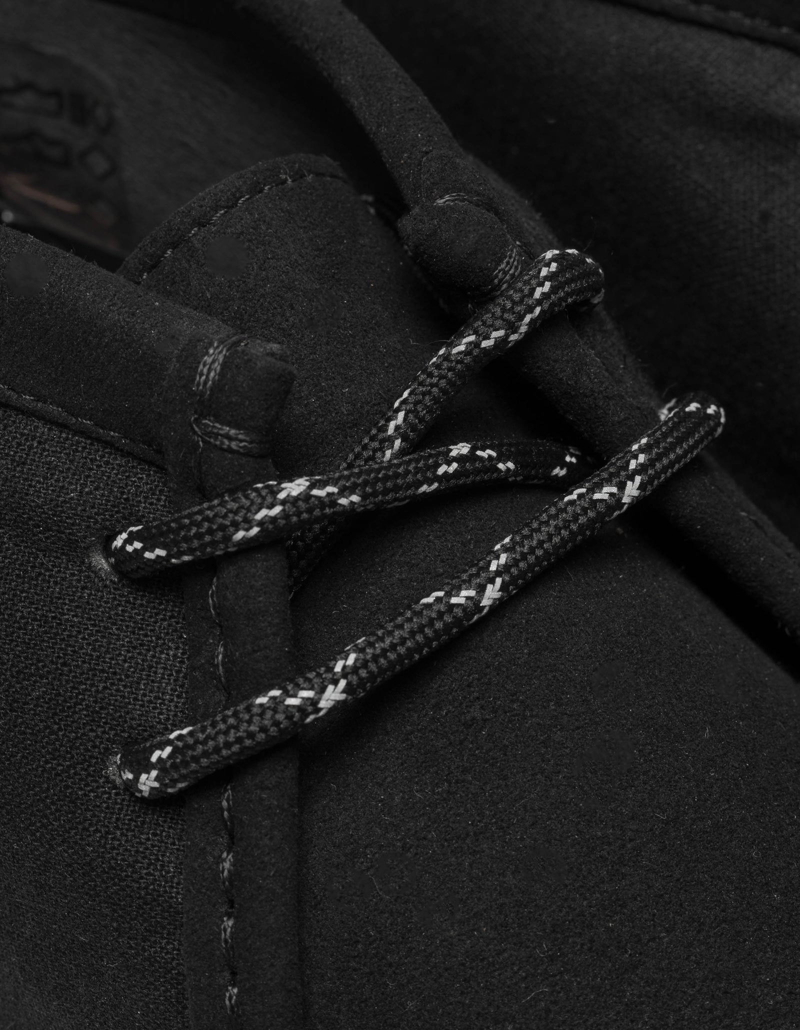 Close-up of black duffel coat with lace-up front on a dark background