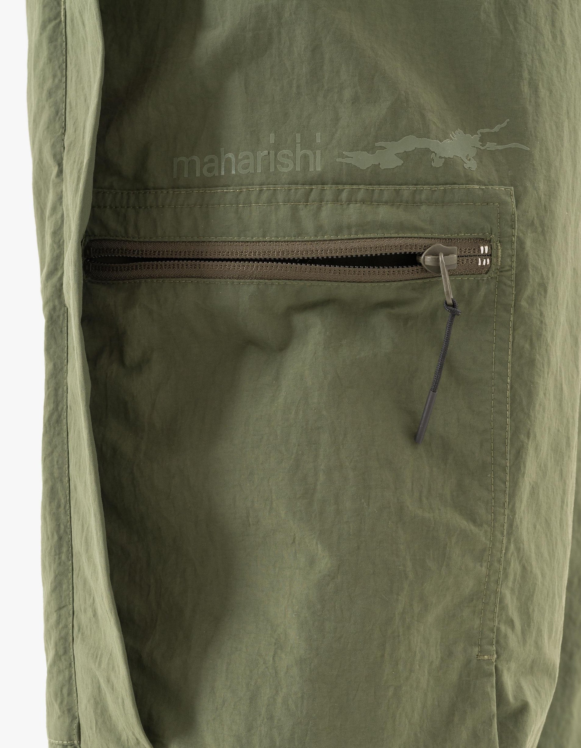 Green jacket with a zipper and 'maharishi' branding on a matching background