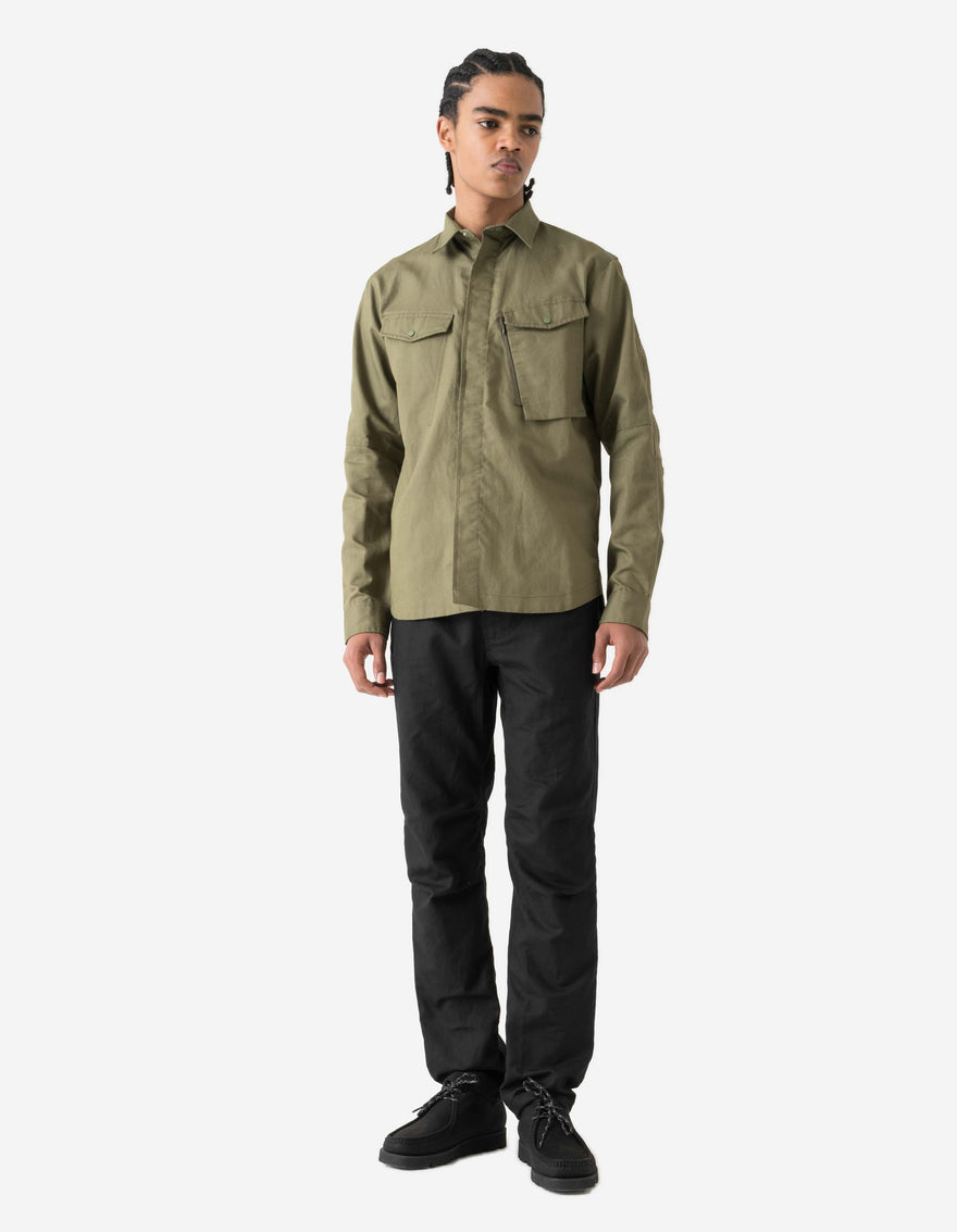 Person wearing a green shirt and black pants on a white background