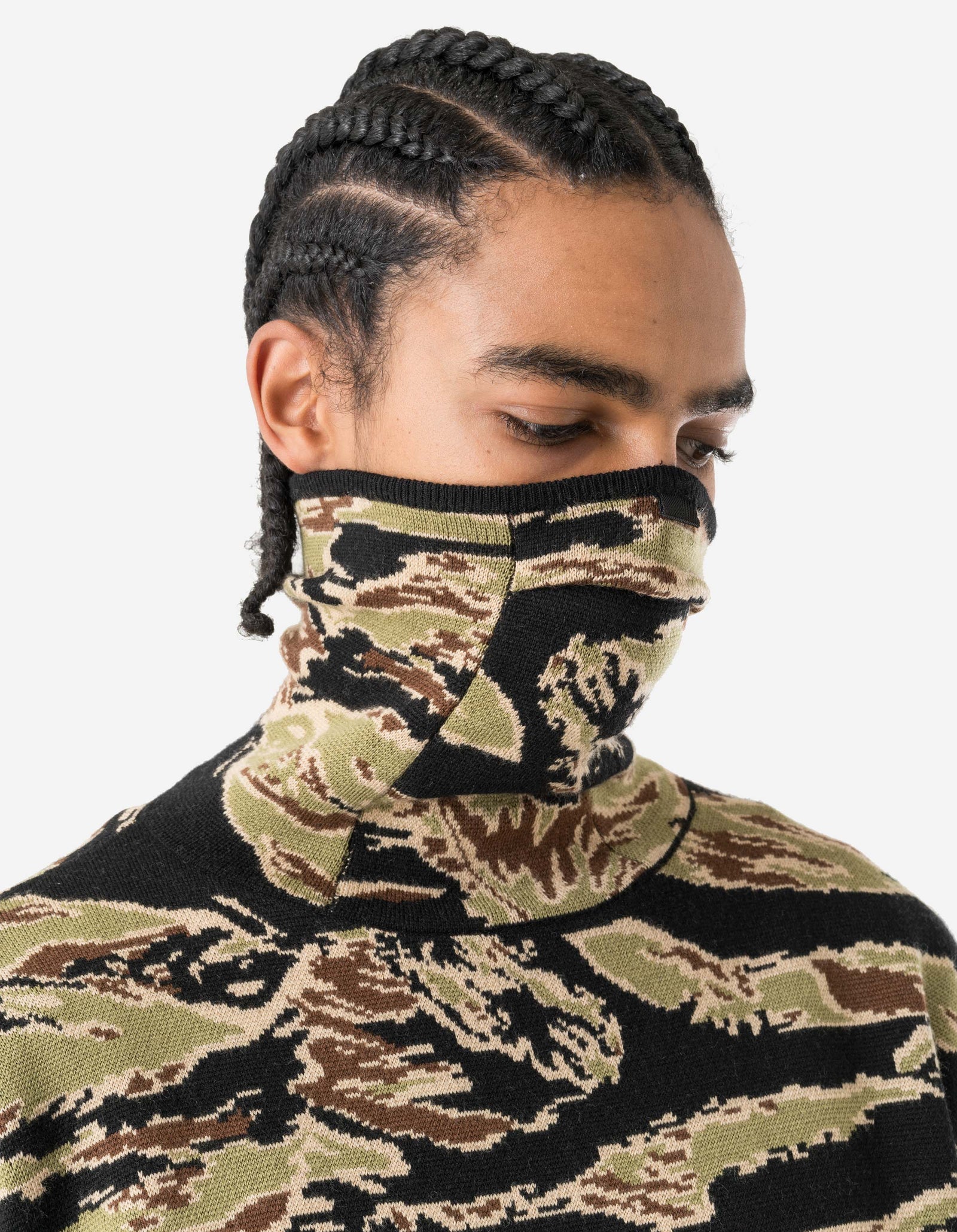 Person wearing a camouflage face mask and sweater on a white background