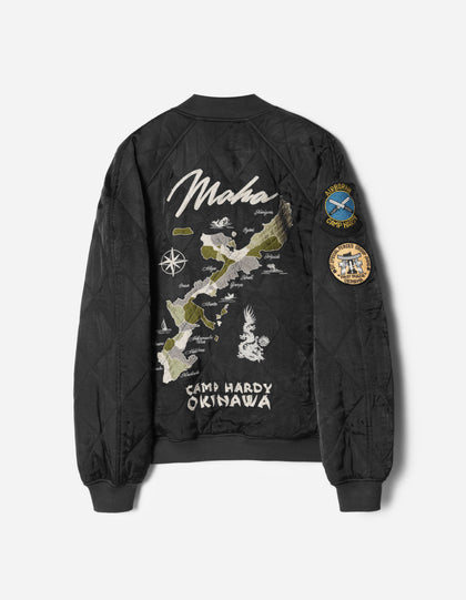 Black bomber jacket with embroidered design and patches on a white background