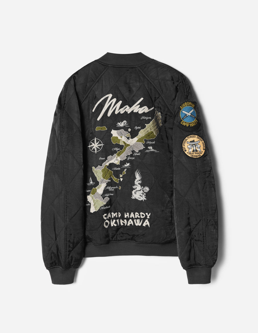 Black bomber jacket with embroidered design and patches on a white background