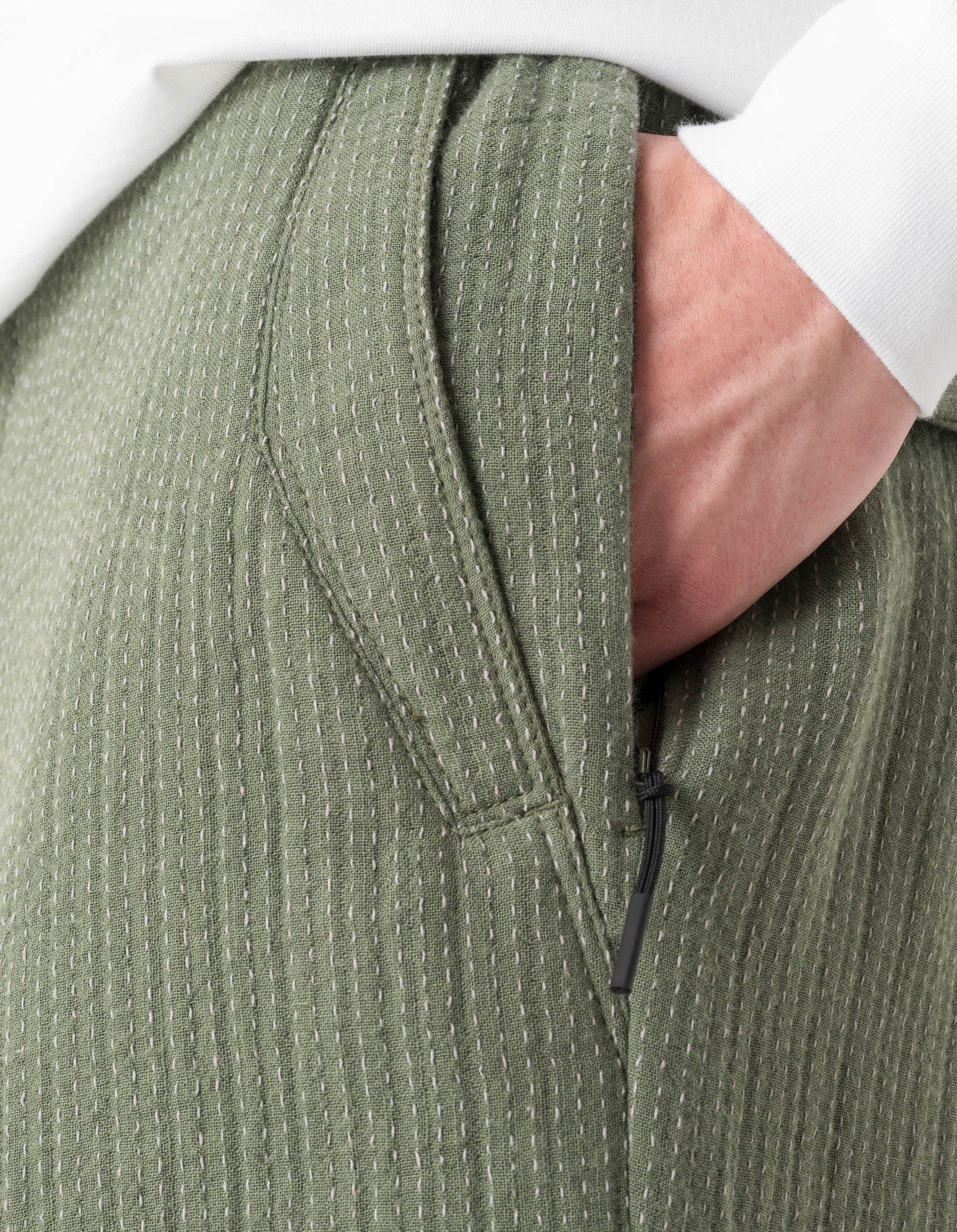 Close-up of a green textured jacket with a zipper, worn by a person.