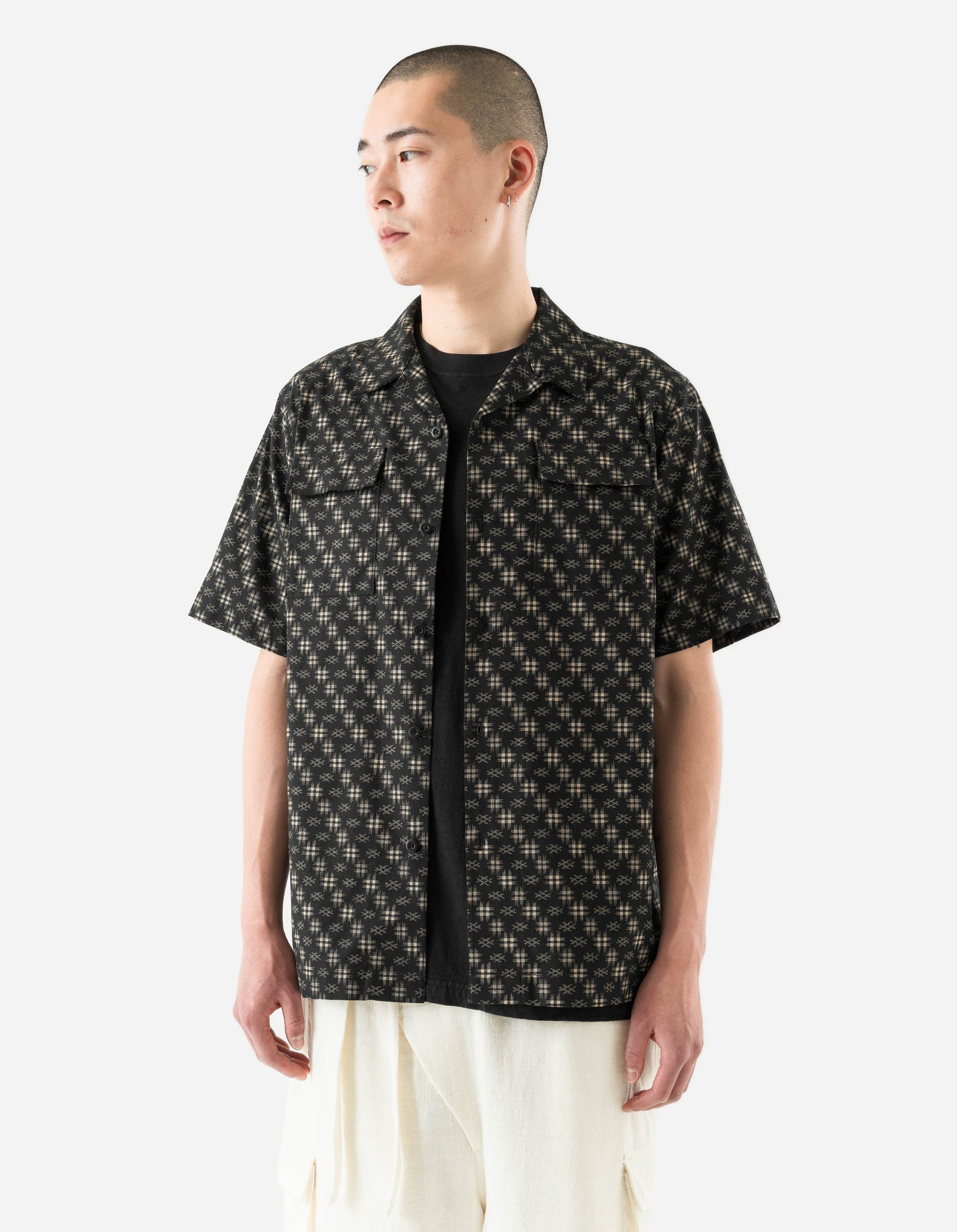 Man wearing a black patterned shirt over a black t-shirt on a white background